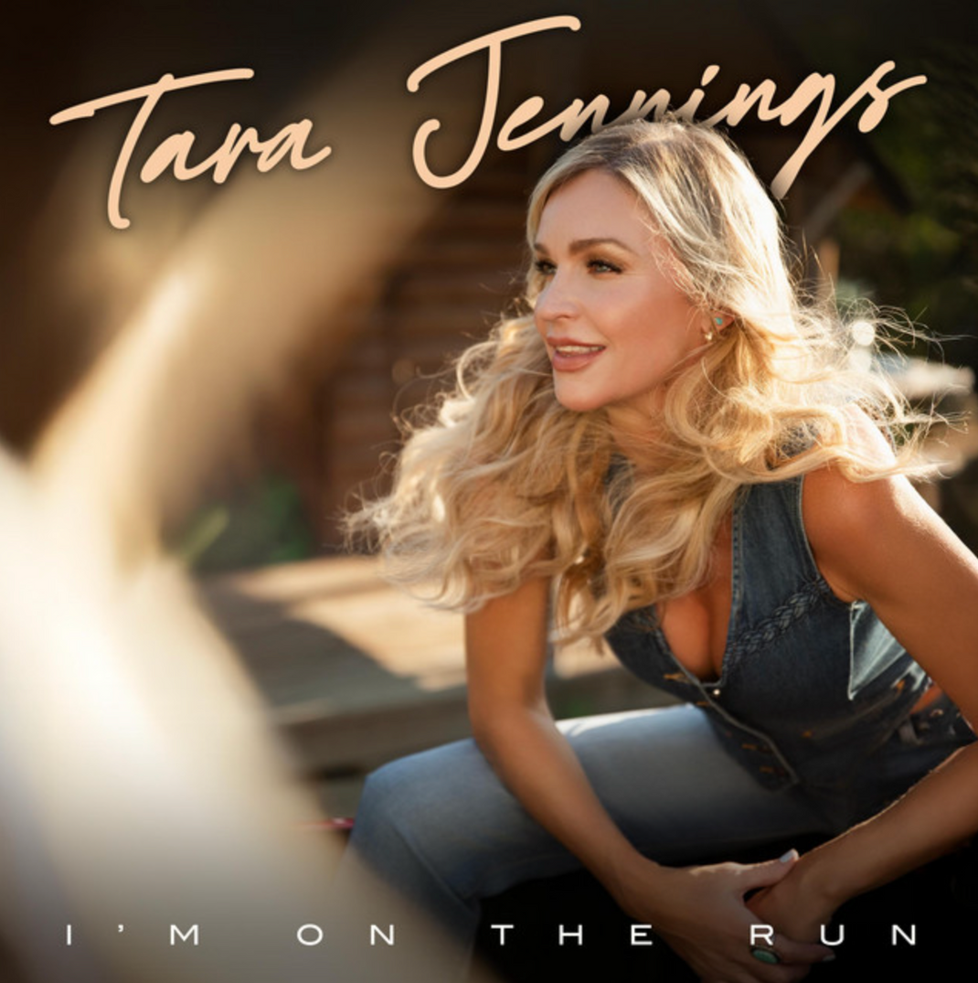 Tara Jennings sitting outdoors on steps, smiling, with long blonde wavy hair, wearing a denim vest. Text reads "Tara Jennings" and "I'm on the Run" — album cover art.
