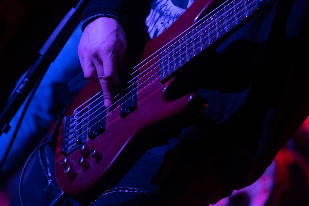 Close-up of a person playing a bass guitar with a dark, moody atmosphere.